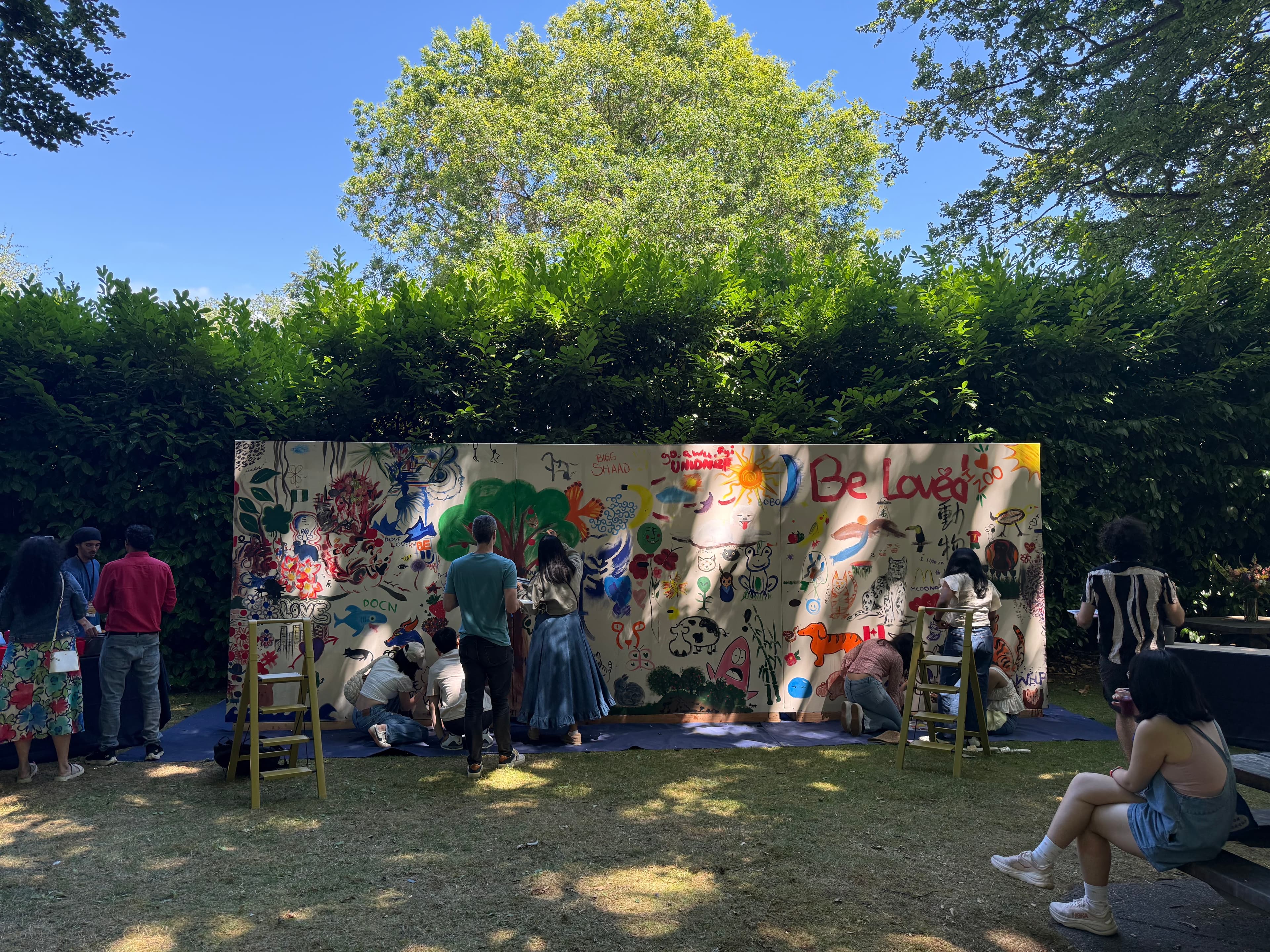 As participation grows, I guide the flow of the wall, manage paint supplies, and help participants build on their ideas, leading to one shared composition.